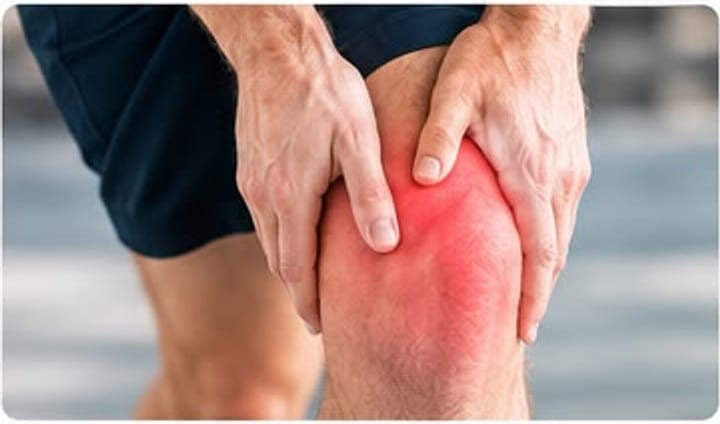 Deportista sujetándose la rodilla, con la articulación marcada en rojo.