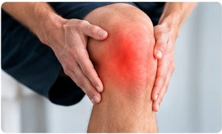 Persona sujetándose la rodilla con ambas manos, con la articulación marcada en rojo.